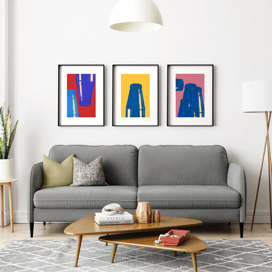 Group of three colorful minimalist graphic art prints on a white wall in a living room.
