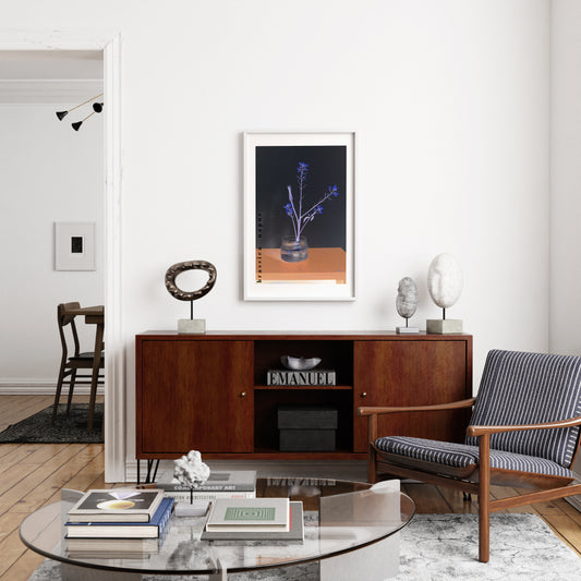 Modern living room with wooden sideboard, striped armchair, glass coffee table and a framed wall art print with plant.