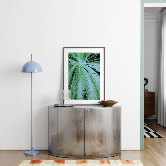 Modern interior with a decorative cabinet, lamp, and framed green leaf print.