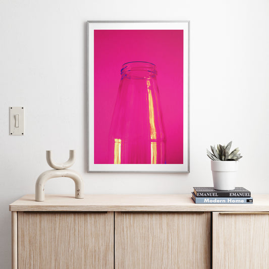 Minimalist intense neon pink art print above a wood sideboard.