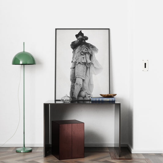 Framed black and white photography art print on a console table with a green floor lamp in a room.