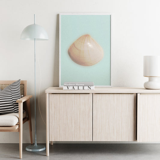 Modern interior with a light wood sideboard, chair, and framed art print with a seashell on the wall.