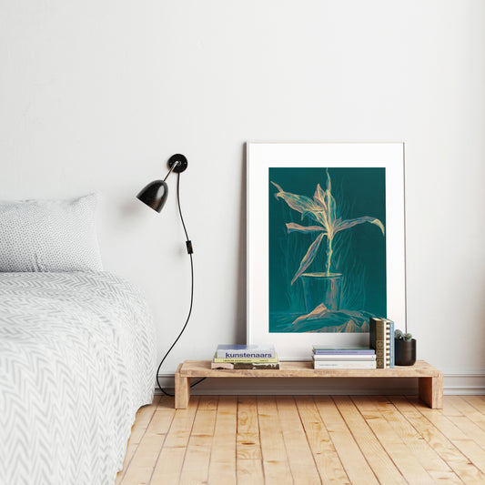 Green still life with plant art print in a bright, minimalist bedroom.