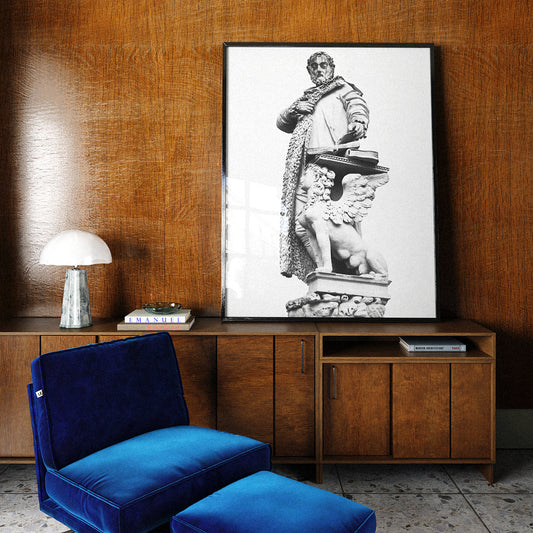 Blue velvet chair and ottoman in front of a wooden cabinet with a framed black and white statue print on the wall.