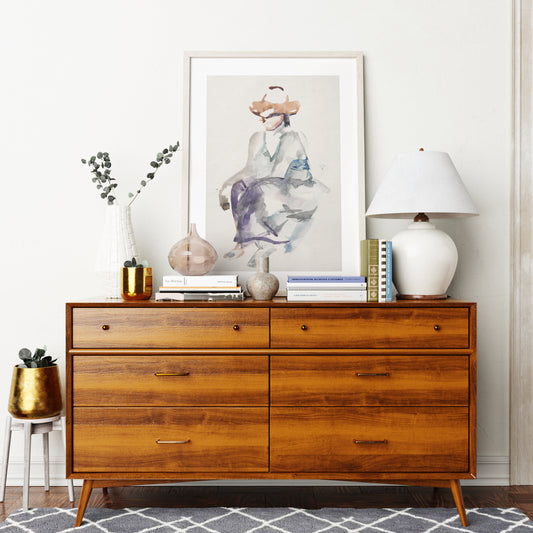 Naive watercolor figure study art print on a mid-century modern sideboard.