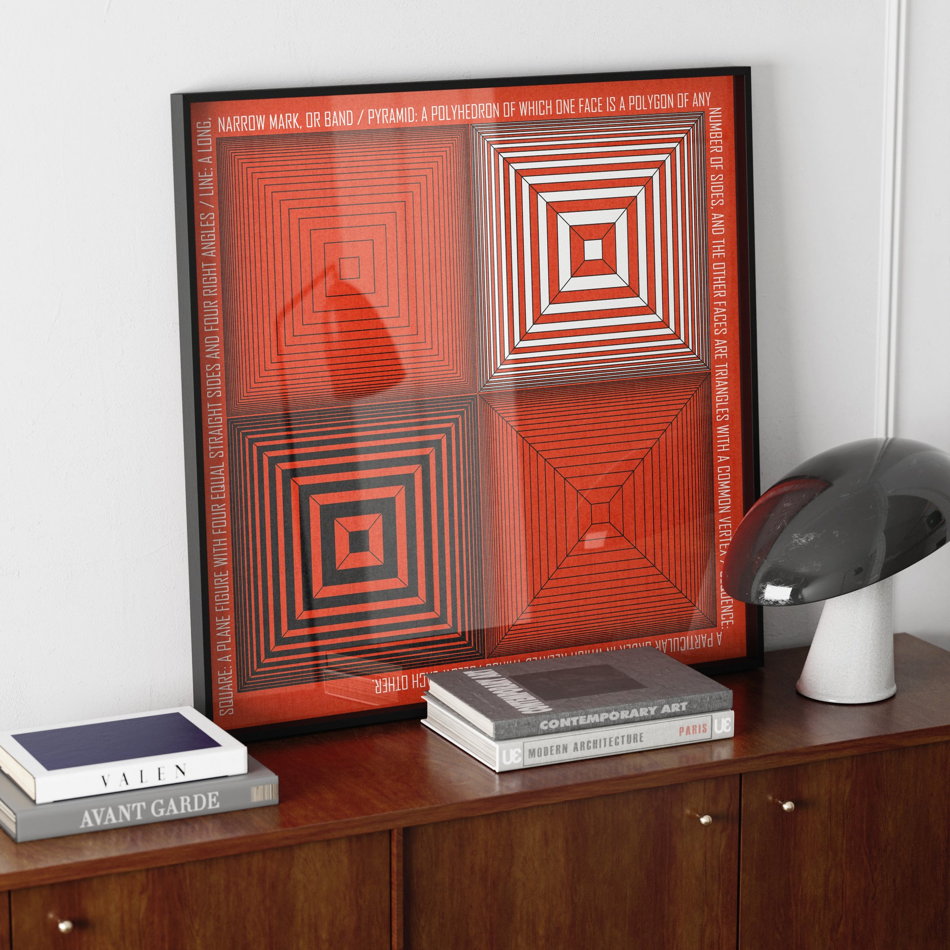Geometric composition art print with red, white and black on a wood sideboard.