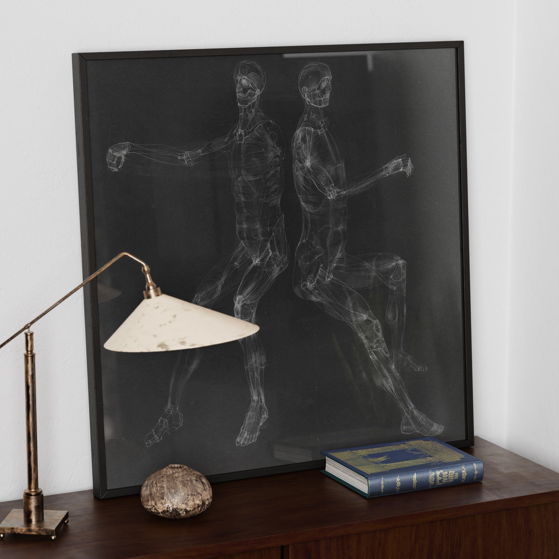 Black and white anatomy art print on a wood sideboard, with two seated figures.