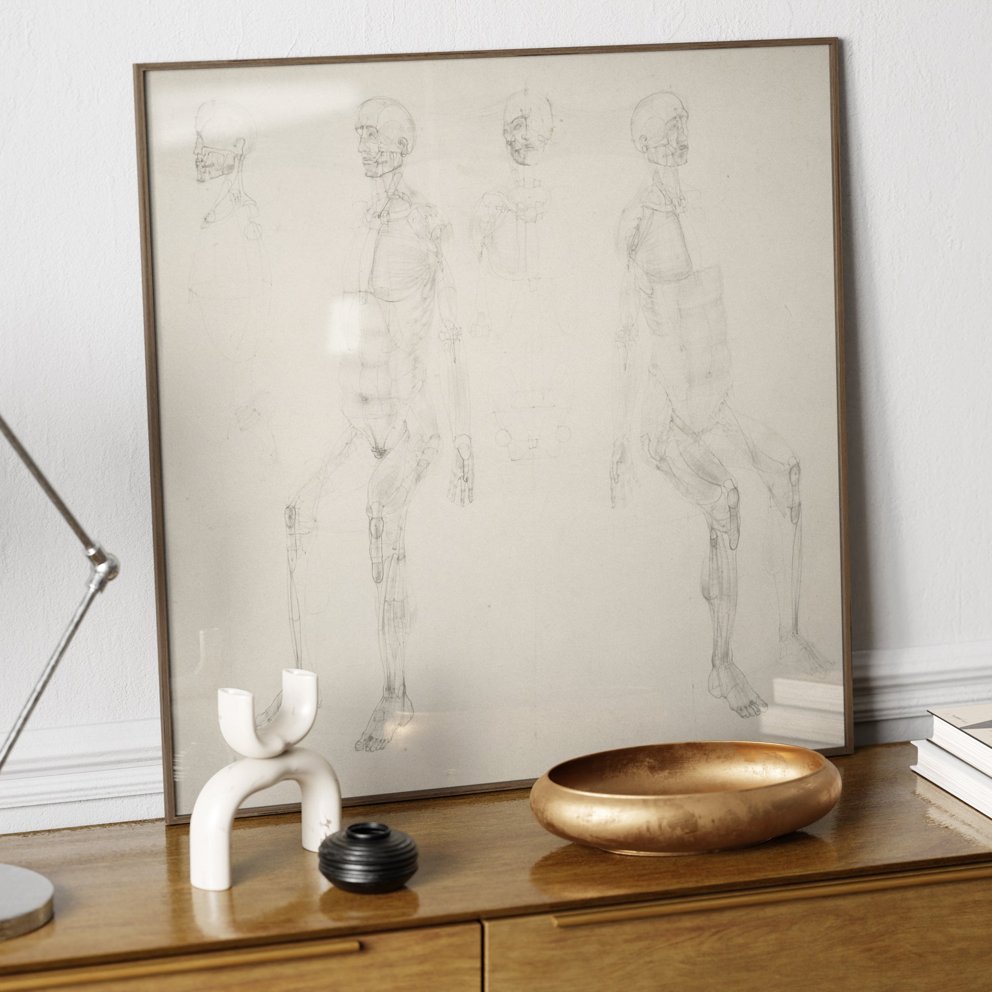 Monochrome anatomy art print with seated figures, on a wood sideboard.