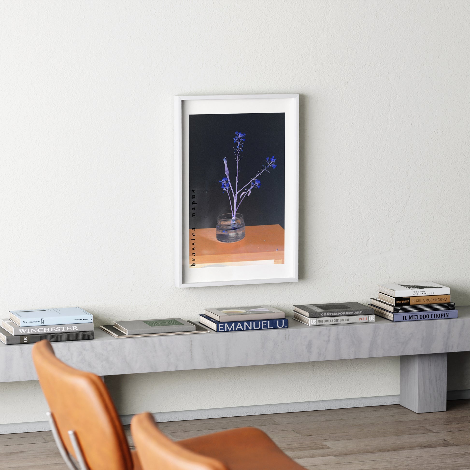 Framed artwork on a wall above a side table with books
