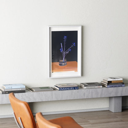 Framed artwork on a wall above a side table with books