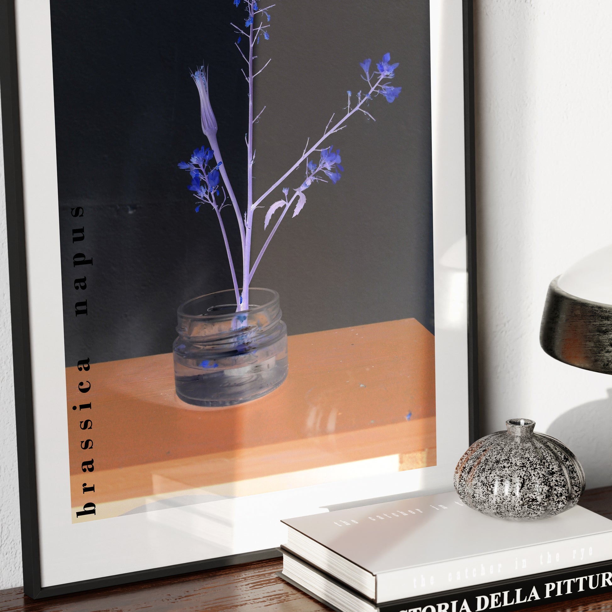 Framed art print of a glass vase with blue flowers on a wooden surface.