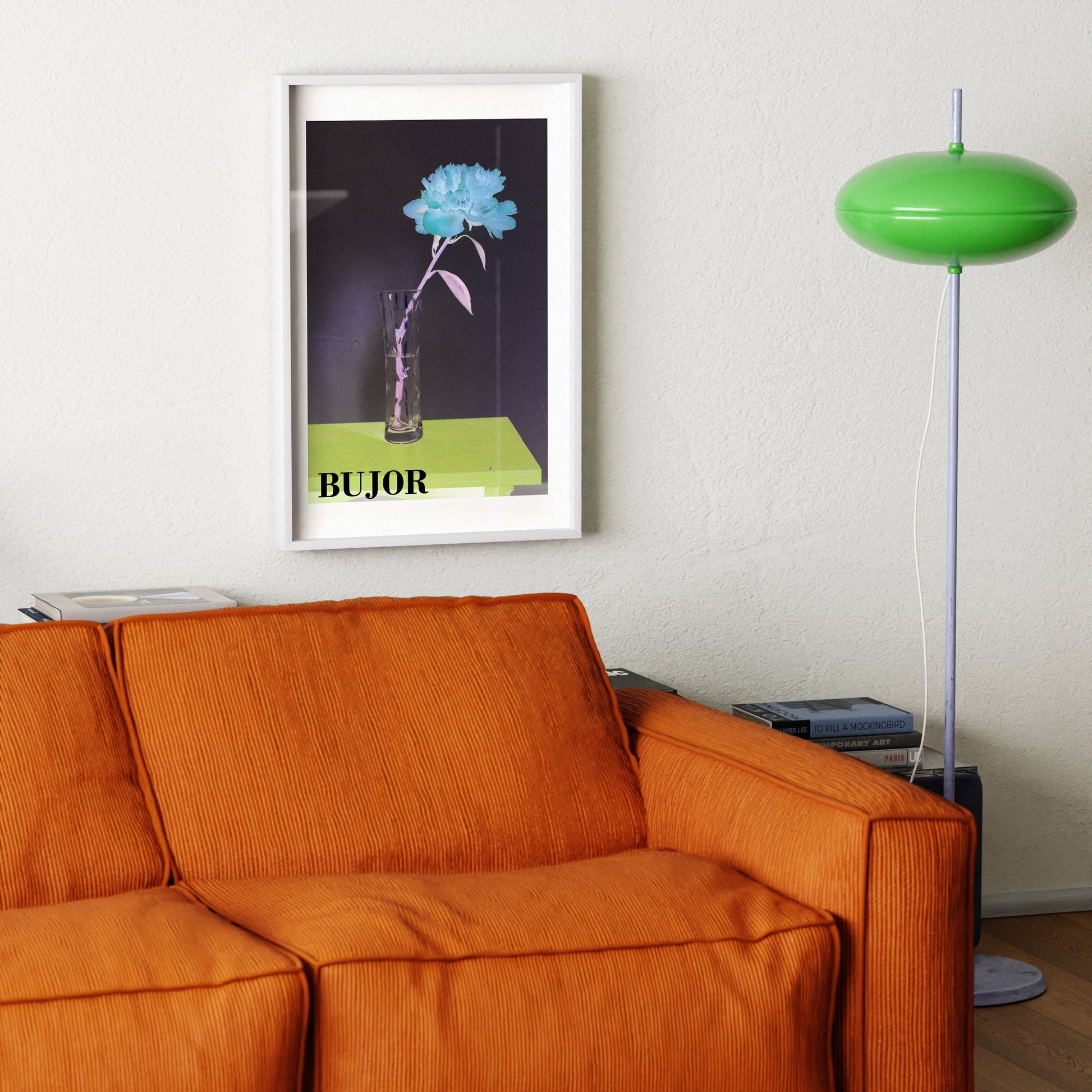 Orange sofa with a framed art print with flower and green floor lamp in a room.