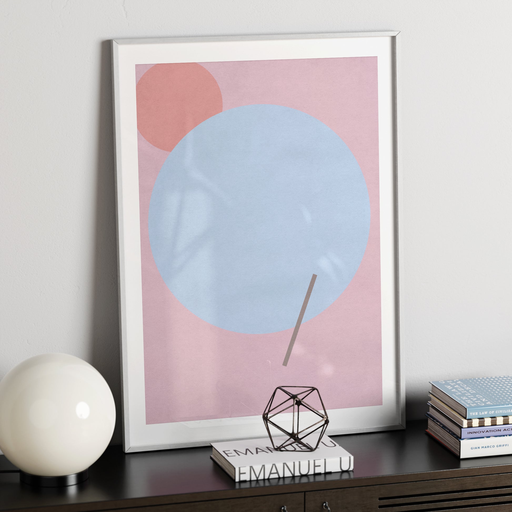 Pink graphic art print with a blue circle, on a modern, metallic black sideboard.