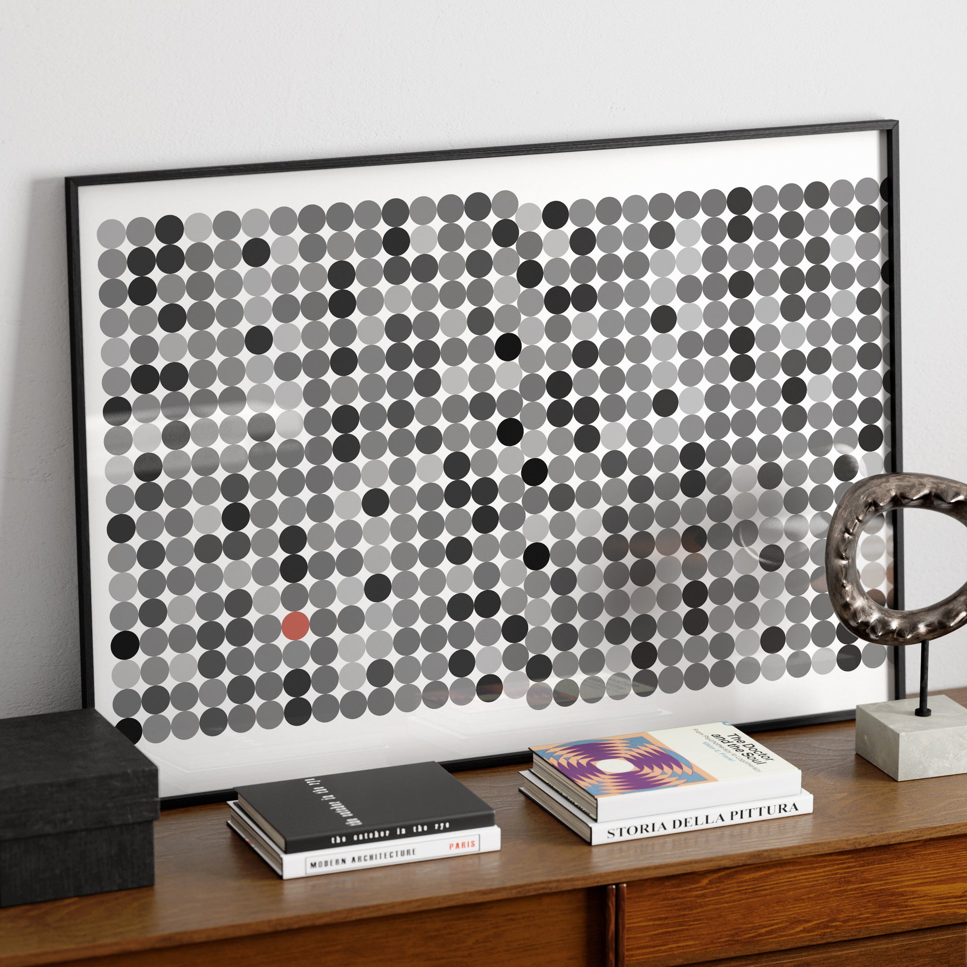 Black and grey dots on a white background, contemporary graphic art print, on a wood sideboard.