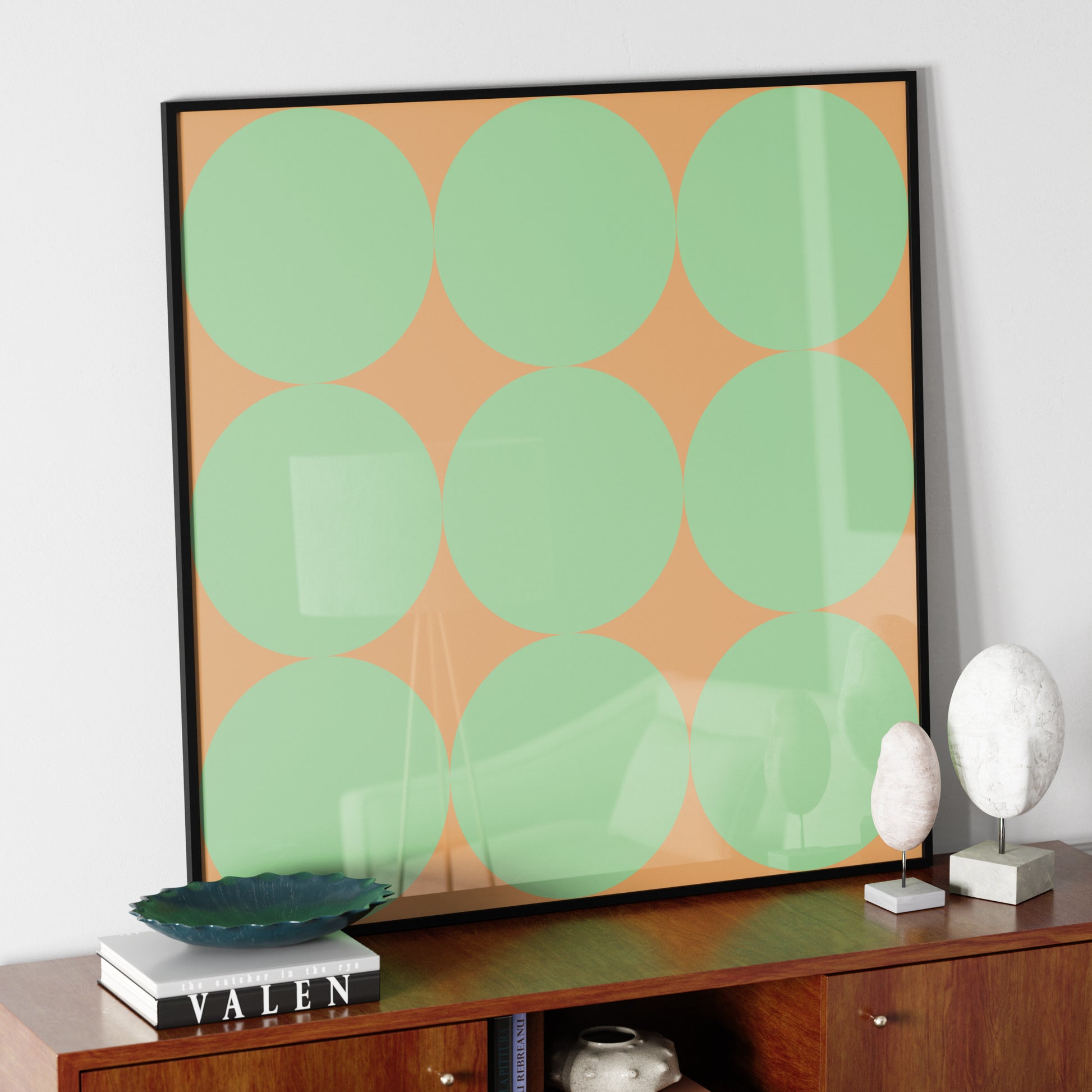 Green dots on a orange background, minimalist graphic art print, on a sideboard.