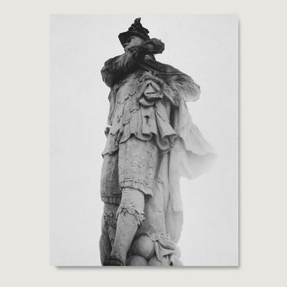 Black and white photography art print with a sculpture of a figure wearing a detailed outfit with ruffles and a hat on a light gray background.