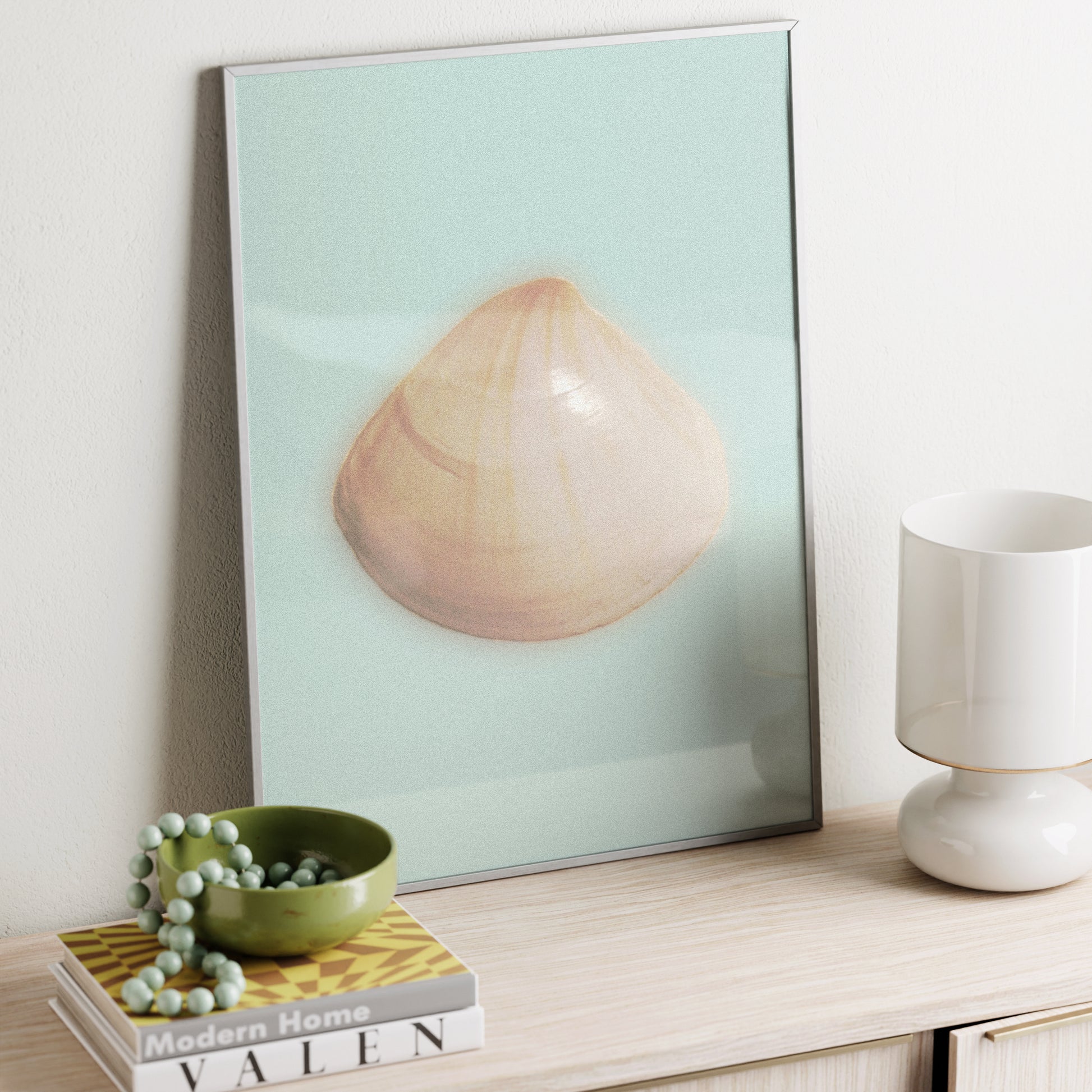 Framed art print of a shell on a shelf with decor items.