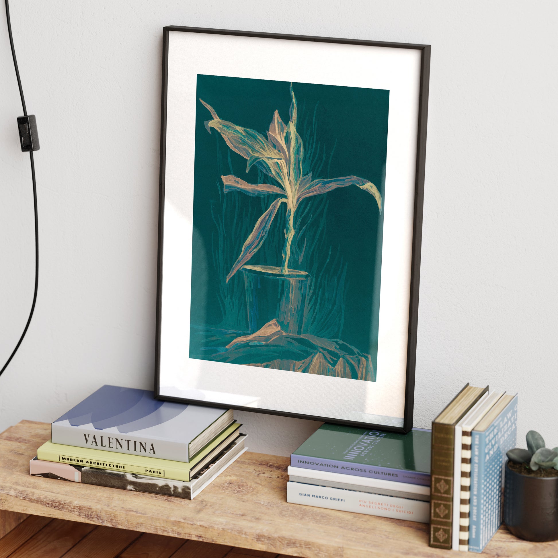 Green still life with plant art print in a black metallic frame.