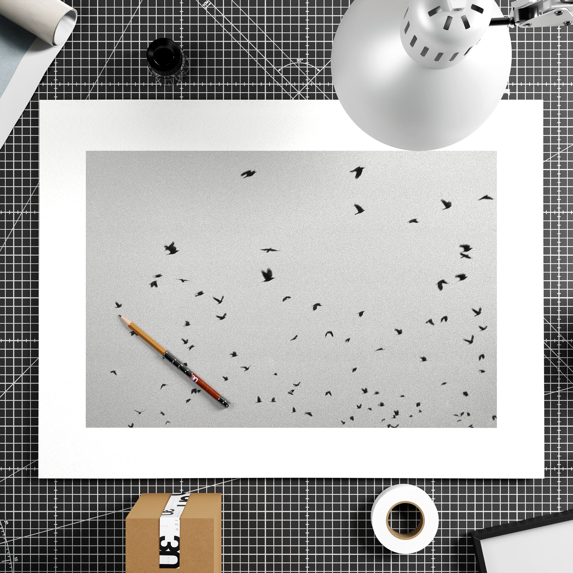 Desk setup with a black and white photography art print, a pencil, and a lamp.