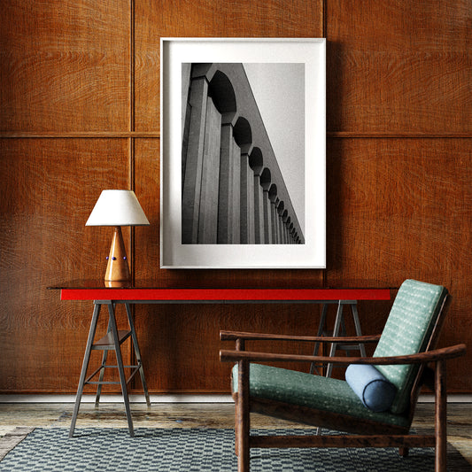 A framed black and white architectural photograph art print in a mid-century modern interior.