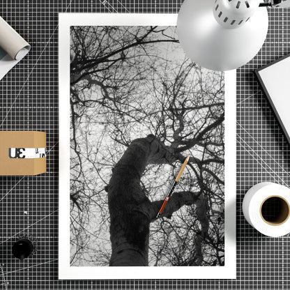 Black and white photo of leafless trees branches, on a grid-patterned surface with stationery items.