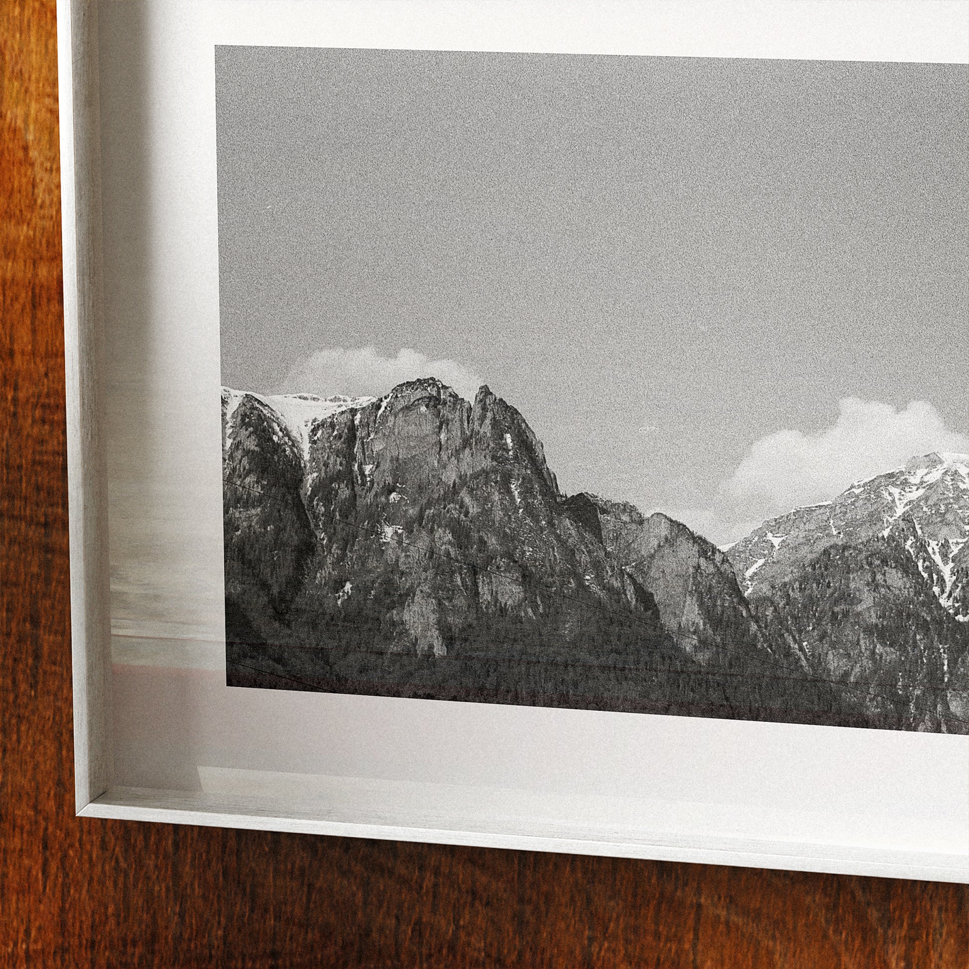 Framed black and white photograph of mountains on a wooden surface