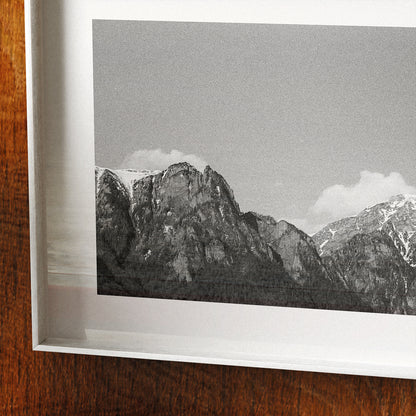 Framed black and white photograph of mountains on a wooden surface