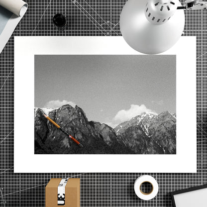 Framed black and white mountain landscape with a red pencil on a grid background