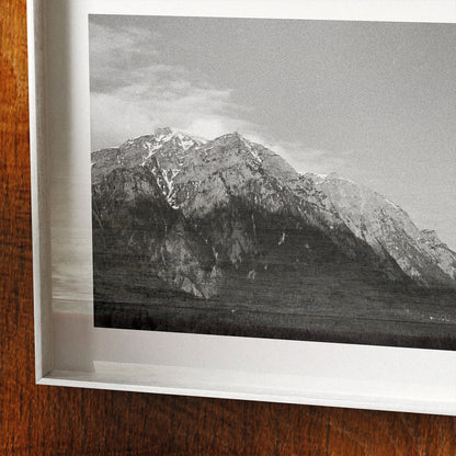 Framed black and white photograph of a mountain landscape on a wooden surface.