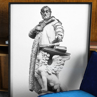 Framed artwork of a classical statue with a blue velvet chair in front.