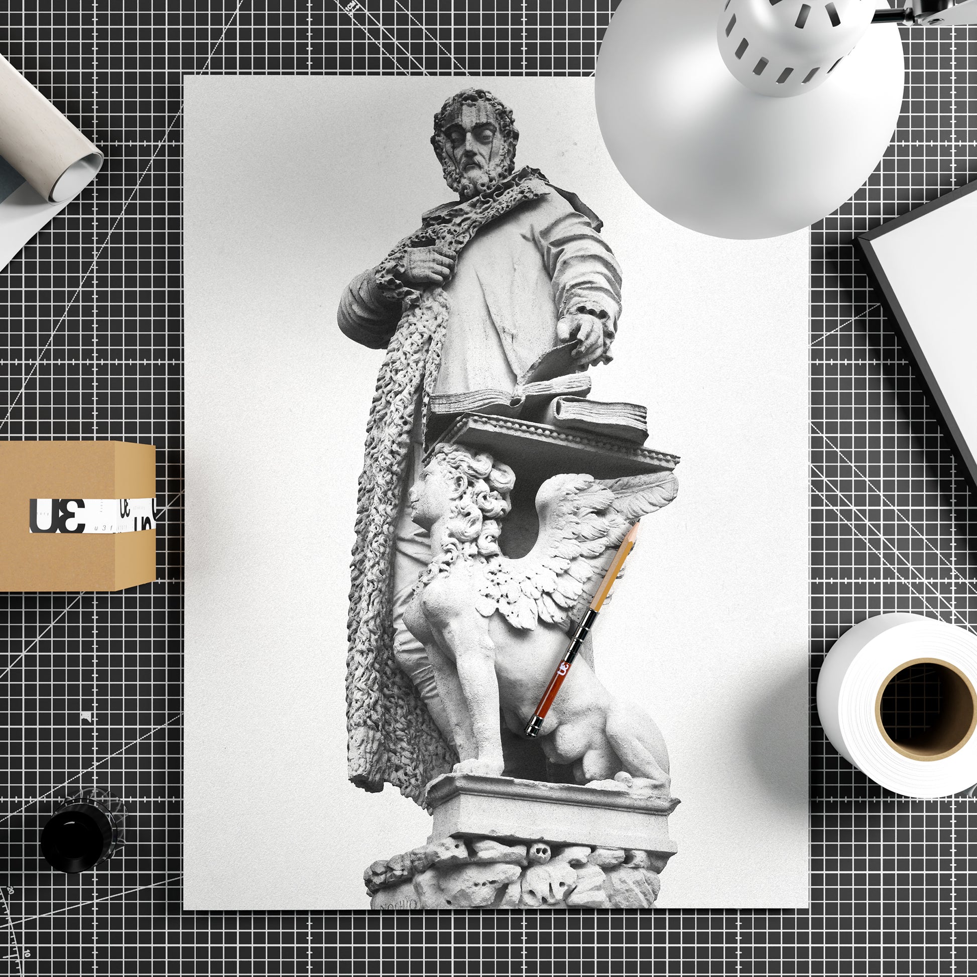 Black and white photography print with a statue on a white background, surrounded by stationery items.