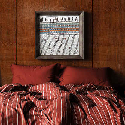 Bed with red striped bedding and pillows against a wooden wall with a framed patterned artwork.